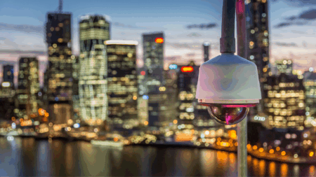 Telecamera di videosorveglianza su skyline urbano al tramonto: sicurezza e tecnologia per smart city moderne, tra innovazione e gestione intelligente dei dati.