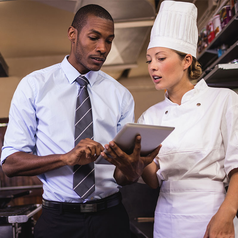 Two hospitality workers using a tablet at work.