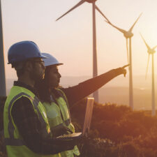 Two wind turbine technicians utilizing a laptop in the field.