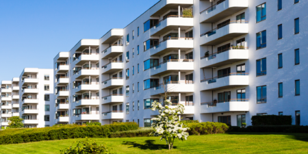 Complesso residenziale moderno con ampie balconate e spazi verdi, sotto un cielo sereno.