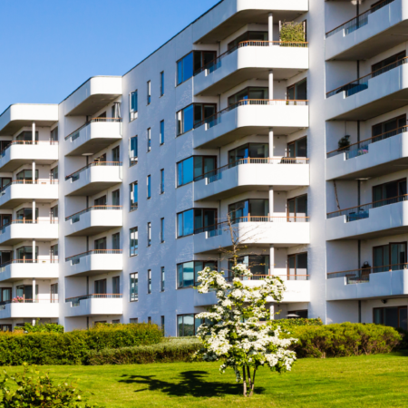 Complesso residenziale moderno con ampie balconate e spazi verdi, sotto un cielo sereno.
