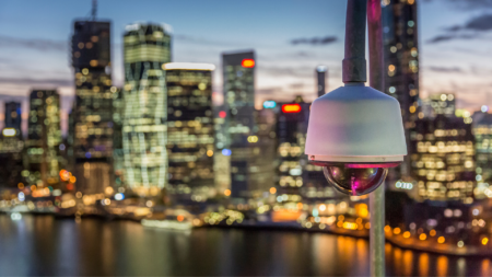 Telecamera di videosorveglianza su skyline urbano al tramonto: sicurezza e tecnologia per smart city moderne, tra innovazione e gestione intelligente dei dati.