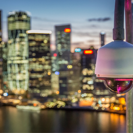 Telecamera di videosorveglianza su skyline urbano al tramonto: sicurezza e tecnologia per smart city moderne, tra innovazione e gestione intelligente dei dati.