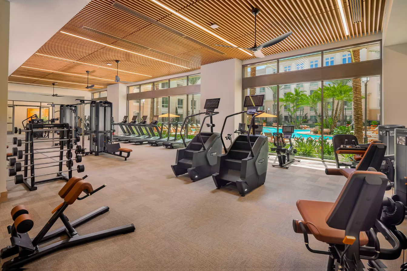 The Pacifica Place fitness center, one of the community amenity spaces covered by managed Wi-Fi, with the pool deck visible through floor-to-ceiling windows